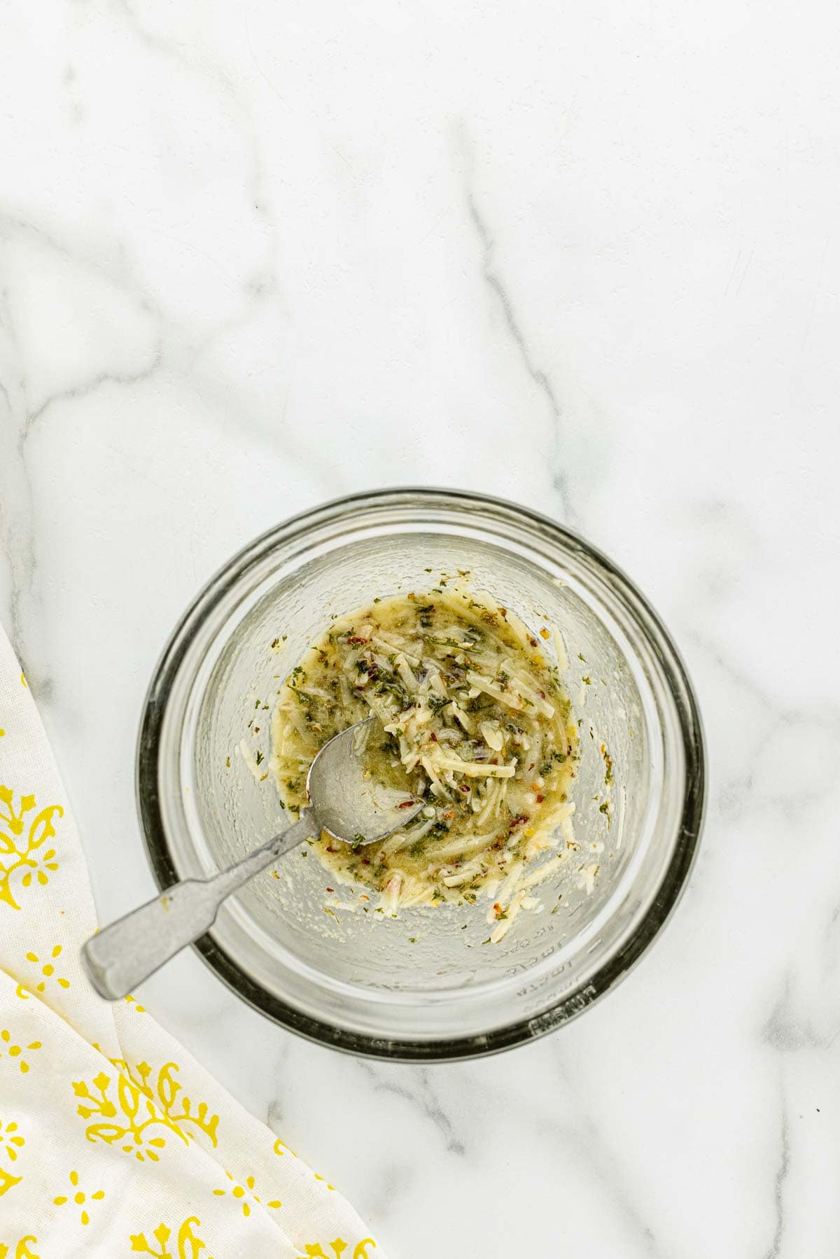 A tiny glass bowl of lemon and parmesan sauce with a spoon.