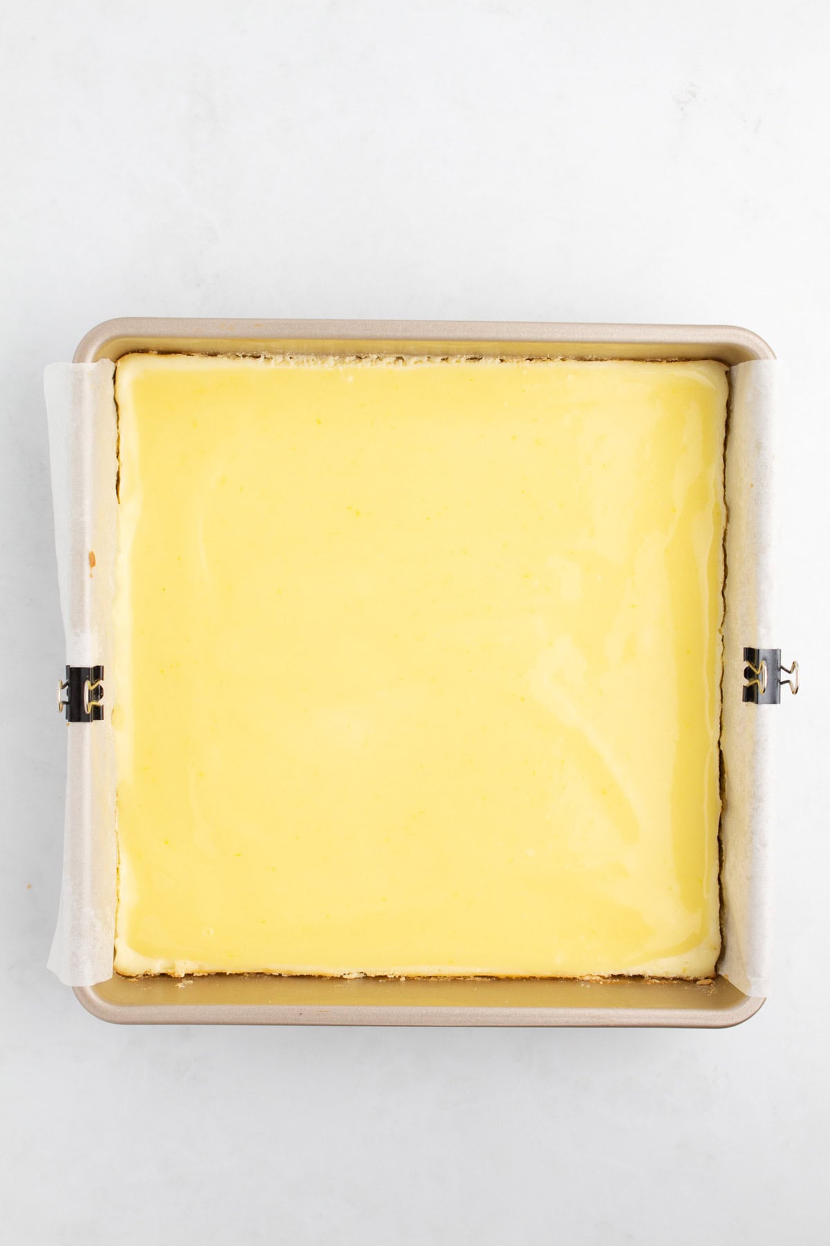 Baked lemon cheesecake with glaze in a baking pan.