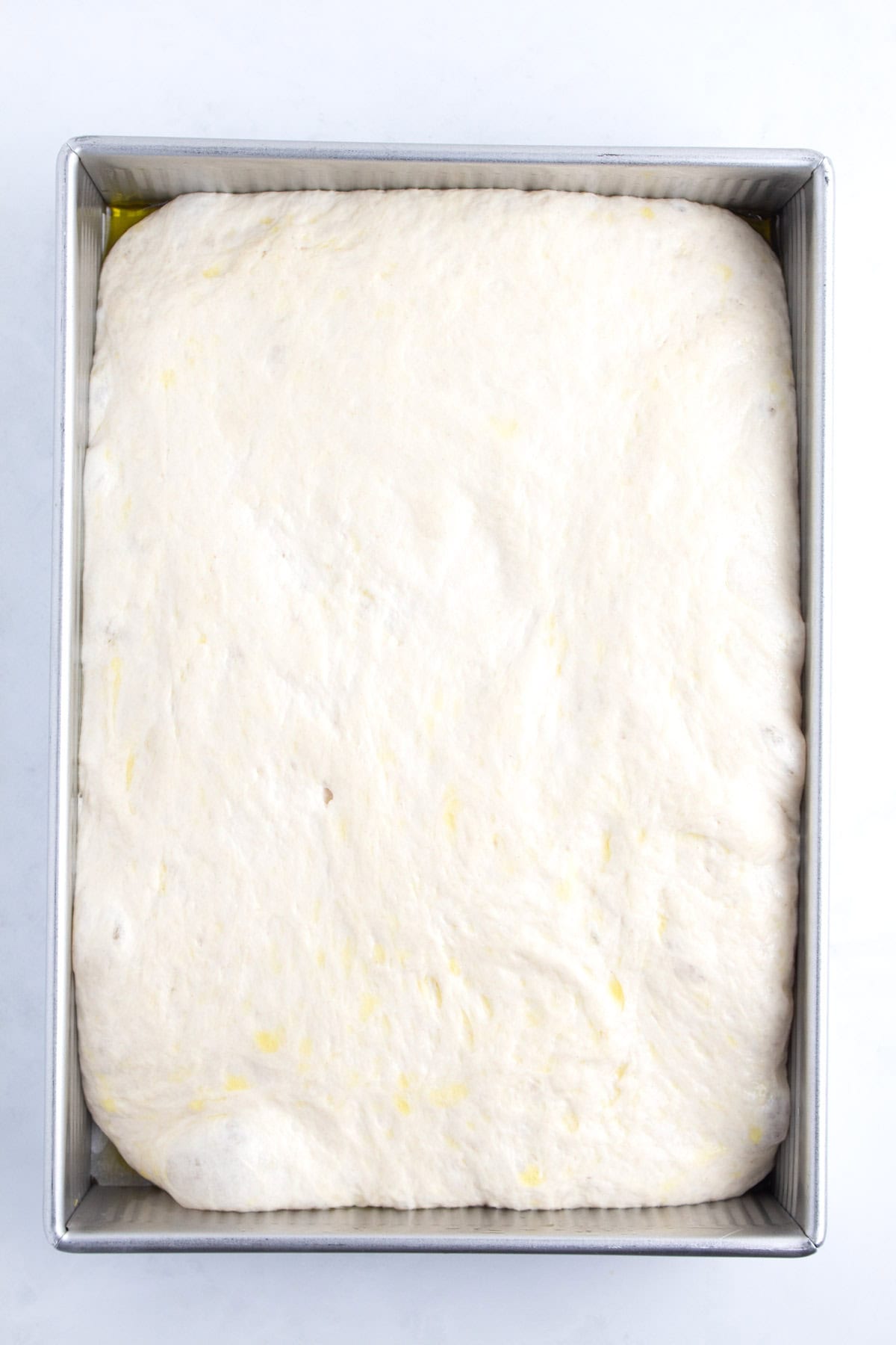 A baking tray completely full of bread dough mixture.