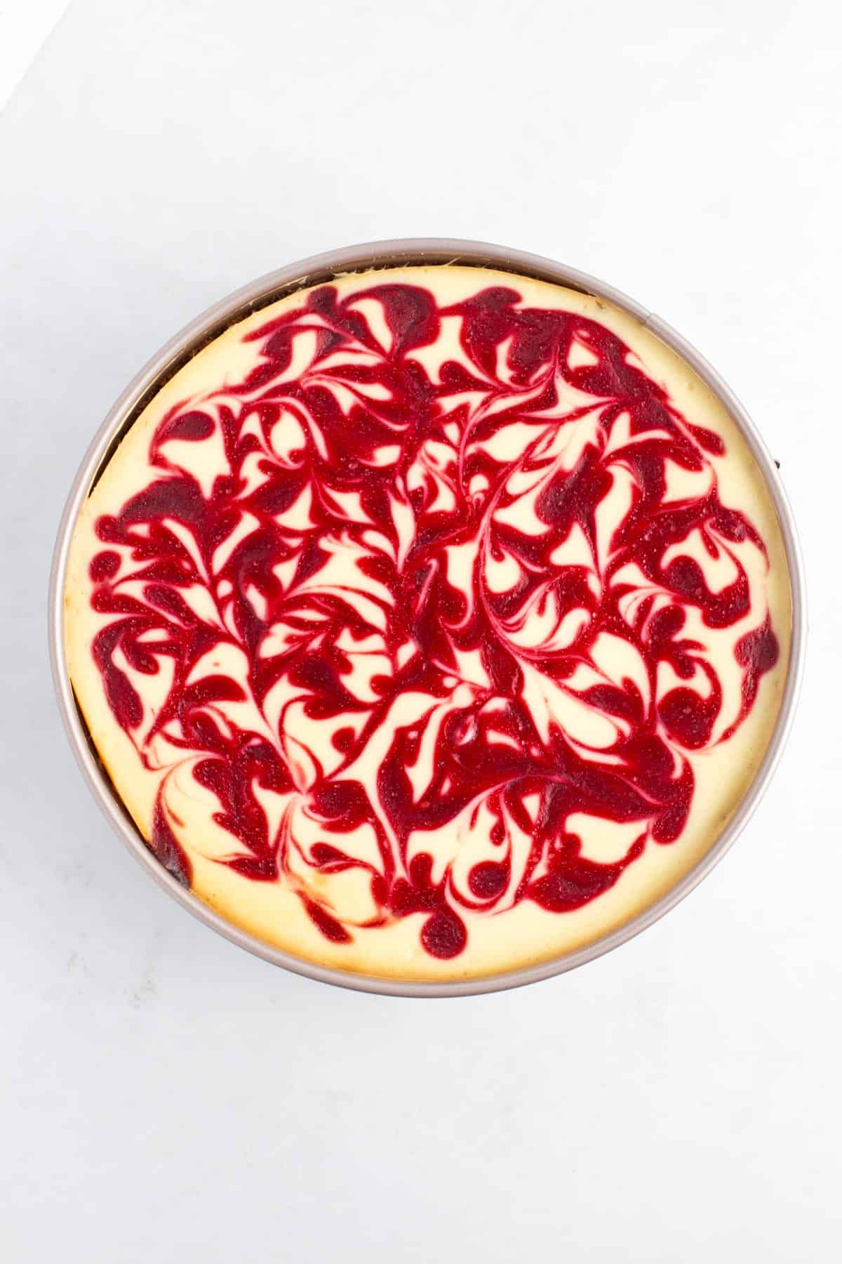 Baked cheesecake with swirled raspberry sauce in it.