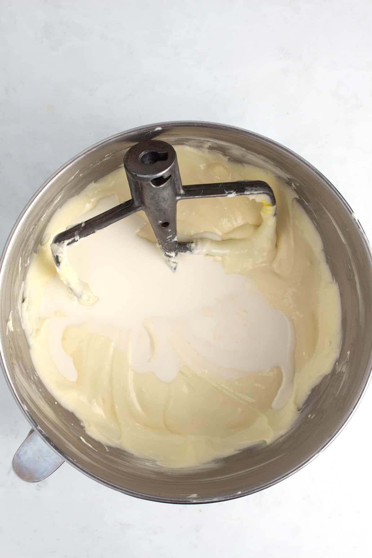 Ingredients getting mixed in a large bowl with a blending paddle in it.