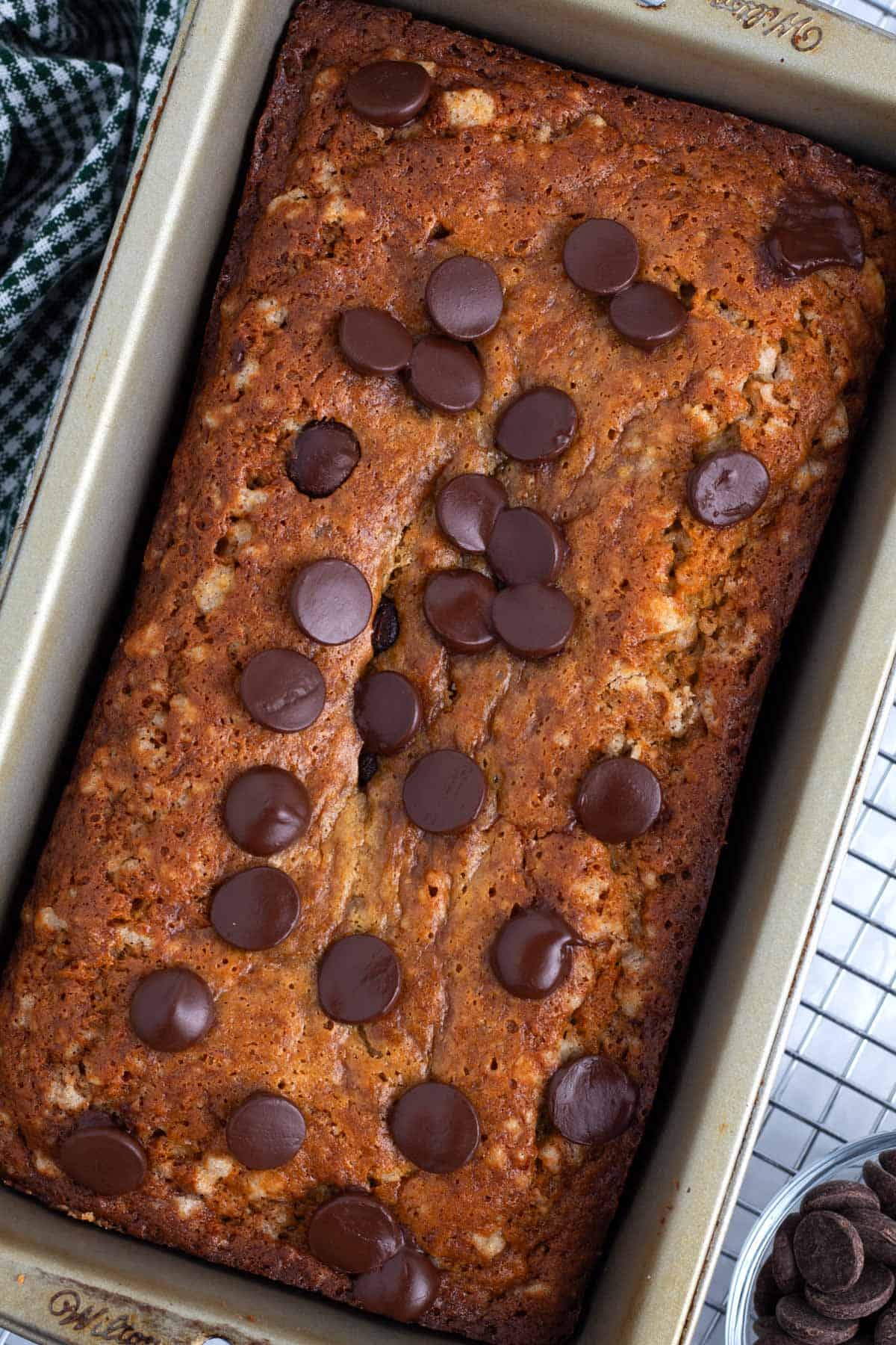 Banana bread with chocolate chips in a baking pan on a wire rack.