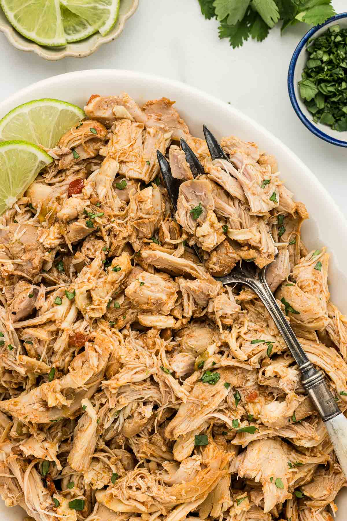 A platter of Mexican chicken with a large serving fork on top.