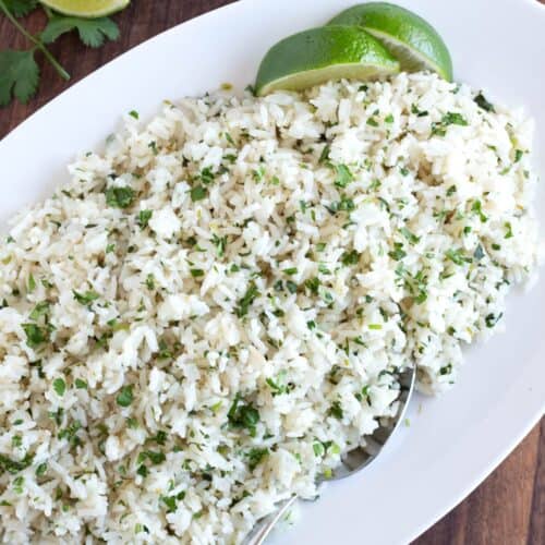 Large serving dish of cilantro lime rice with limes.