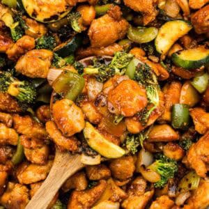 Gochujang chicken stir fry with a wooden spoon taking a scoop out.