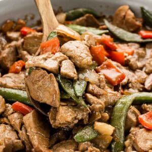 A wooden spoon scooping up a serving of teriyaki stir fry.