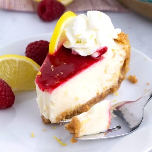 A serving of lemon pie with raspberry sauce with a piece of it on a fork next to the slice.