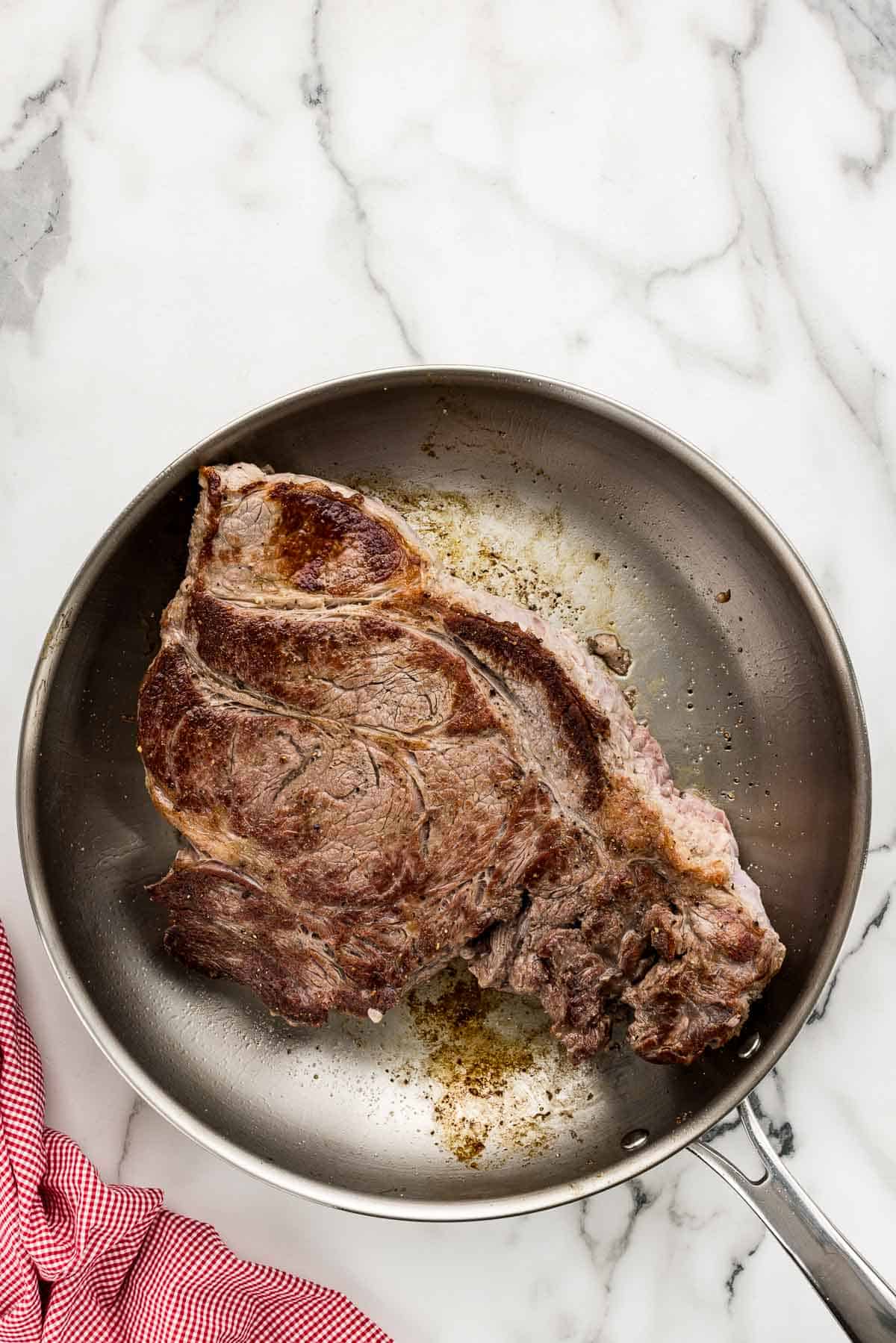 A large piece of beef in a silver pan.