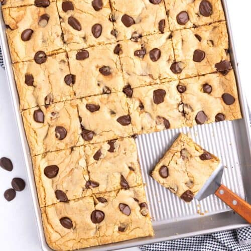 Chocolate chip bars in a baking pan with a piece on a spatula.