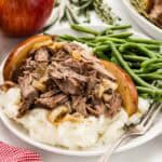 A serving of apple cider chuck roast with a side of green beans and mashed potatoes.