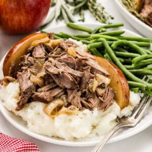 A serving of apple cider chuck roast with a side of green beans and mashed potatoes.