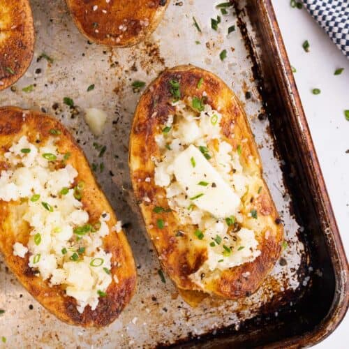 Melted butter on two baked potato halves sitting on a tray.