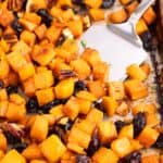 Roasted sweet potatoes on a cooking pan with a serving spatula.