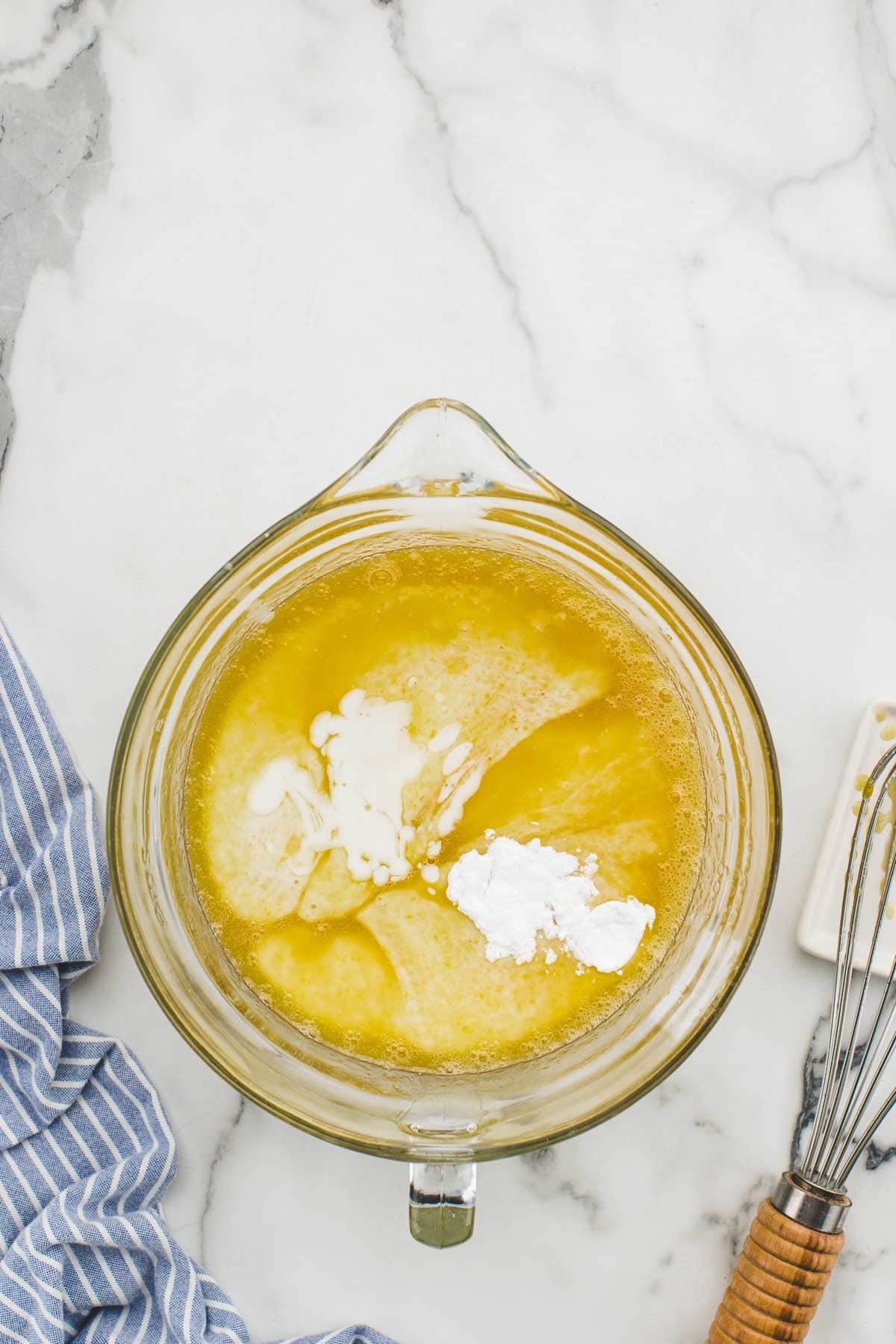 Wet ingredients in a glass mixing dish with a whisk.