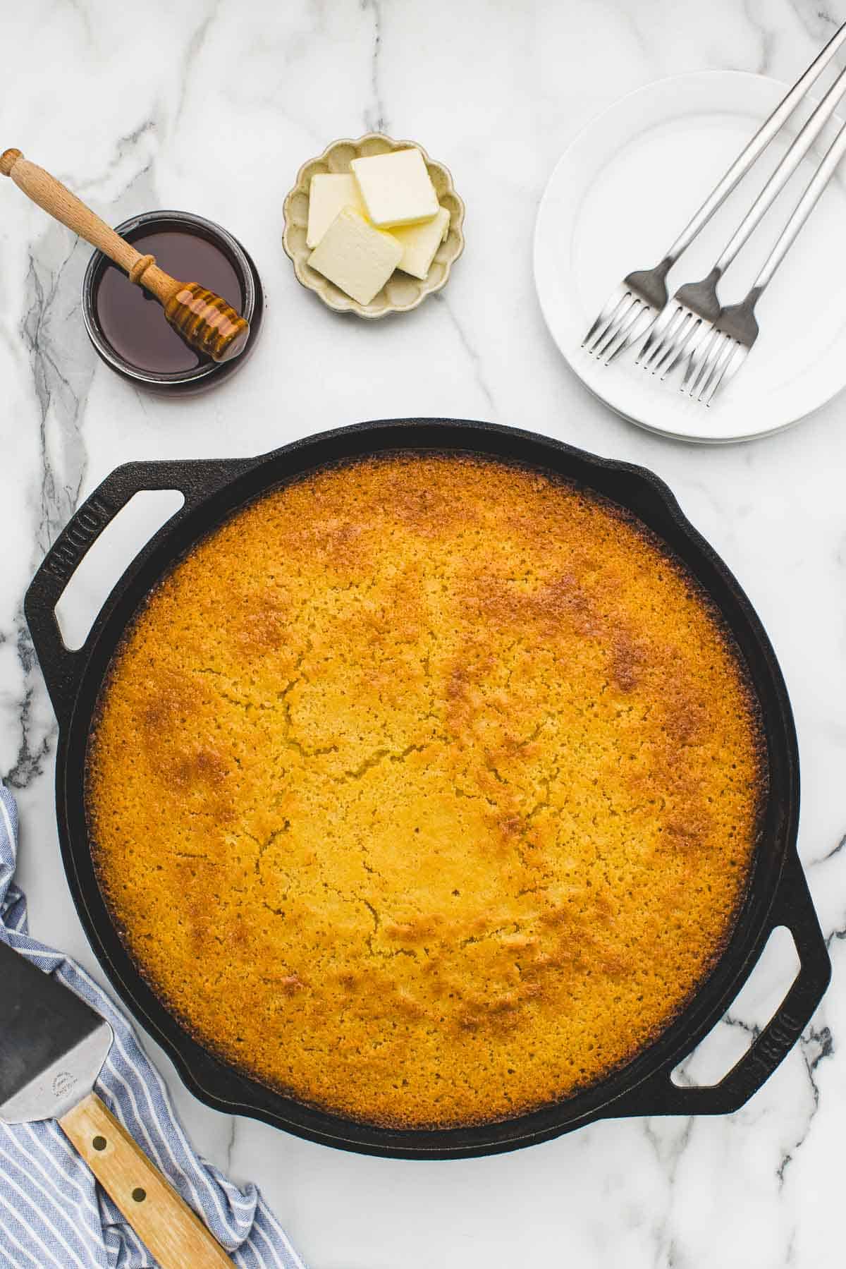 Baked cornbread in a cast iron skillet surrounded by an array of toppings.