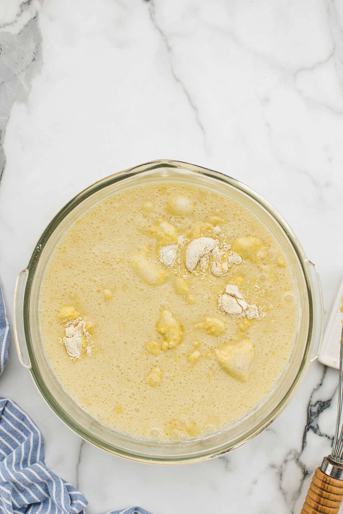 A large glass bowl of unmixed cornbread batter.