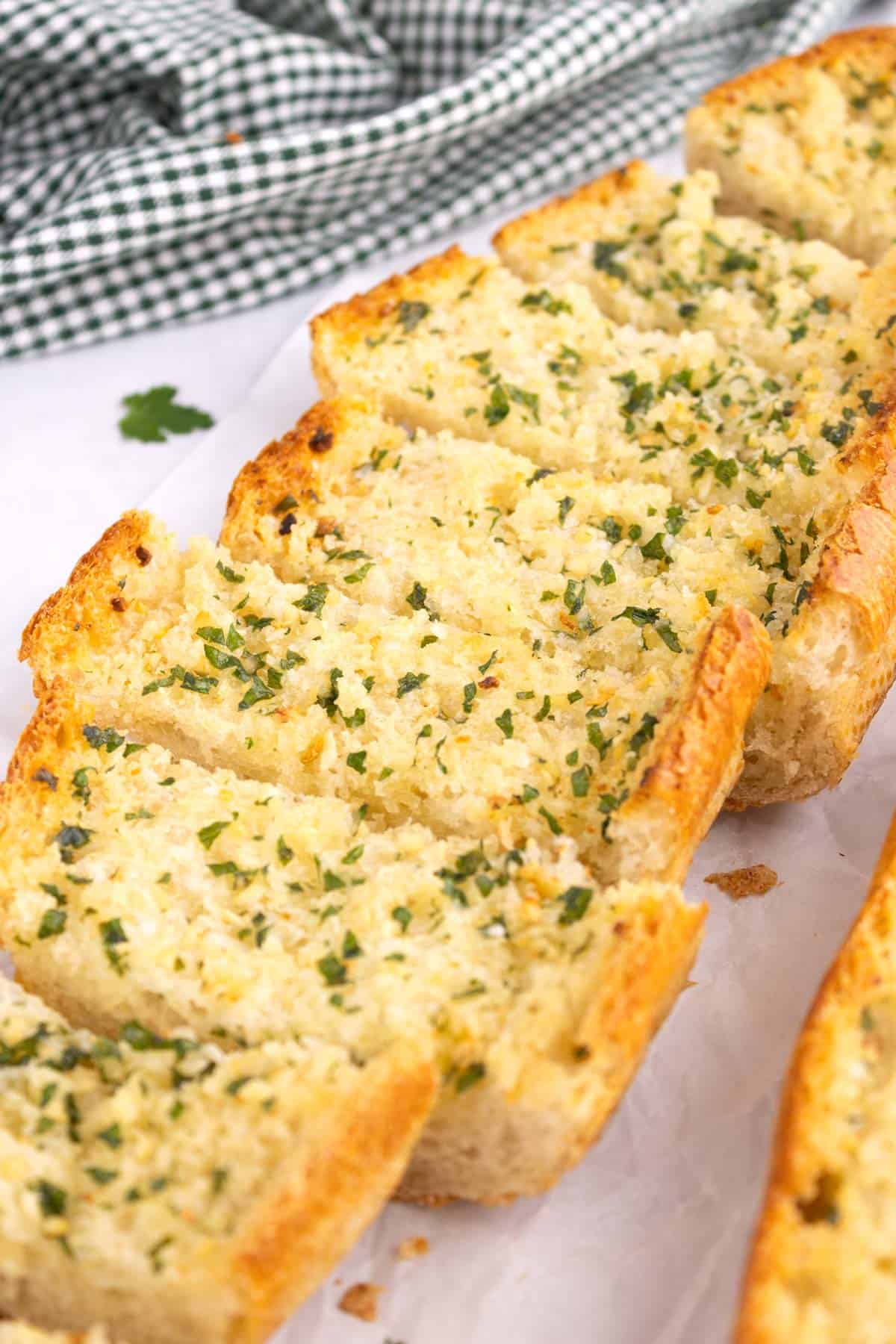 Garlic bread cut into slices on parchment paper.