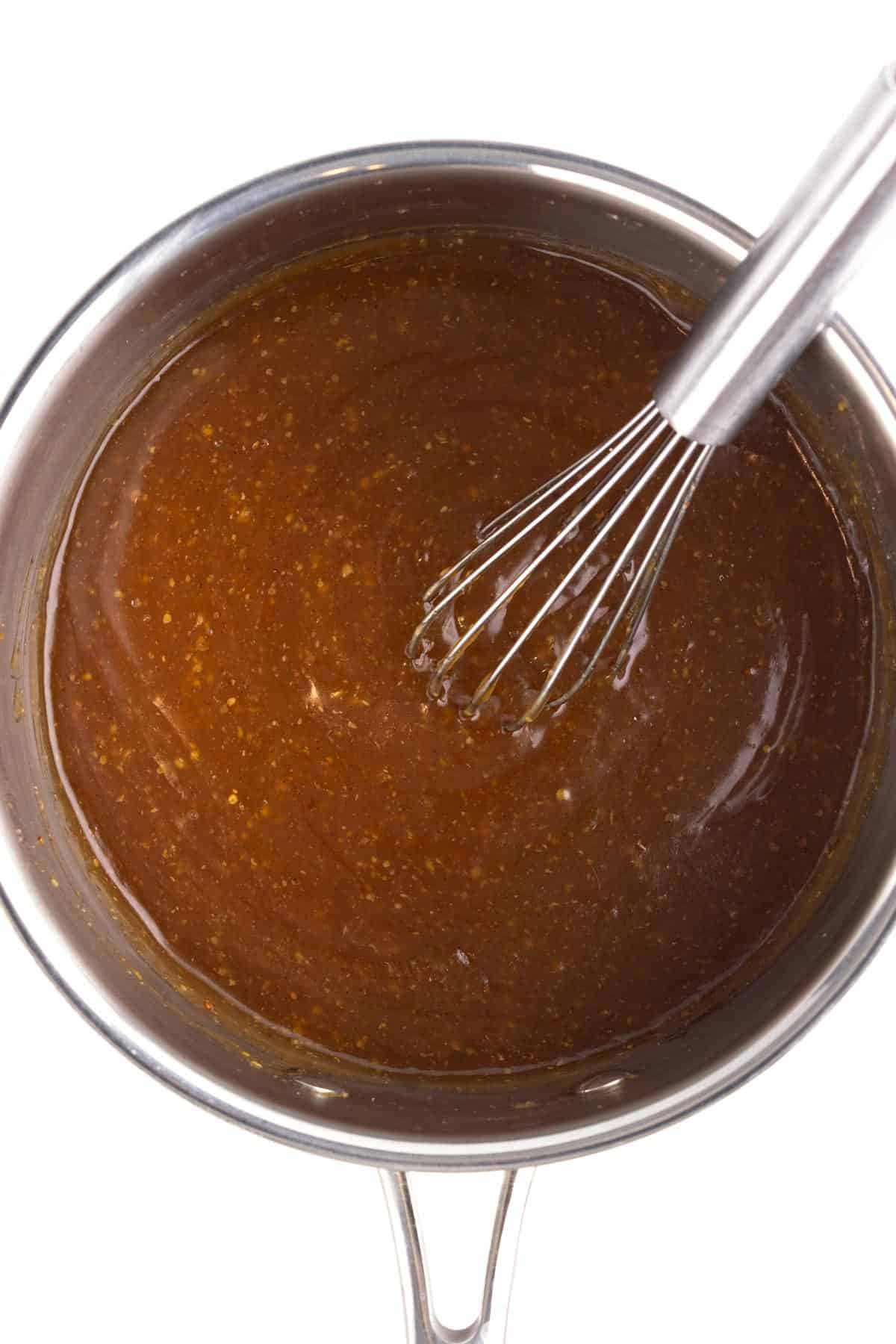 Ham glaze in a saucepan with a whisk.