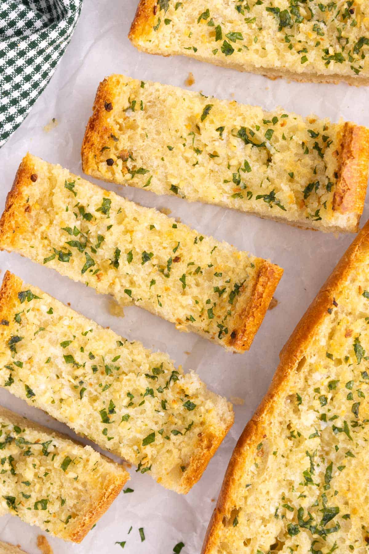 Garlic bread slices spread out on parchment.