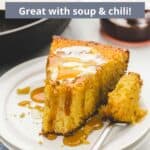 A slice of cornbread drenched in hot honey on a white plate with a graphic overlay.