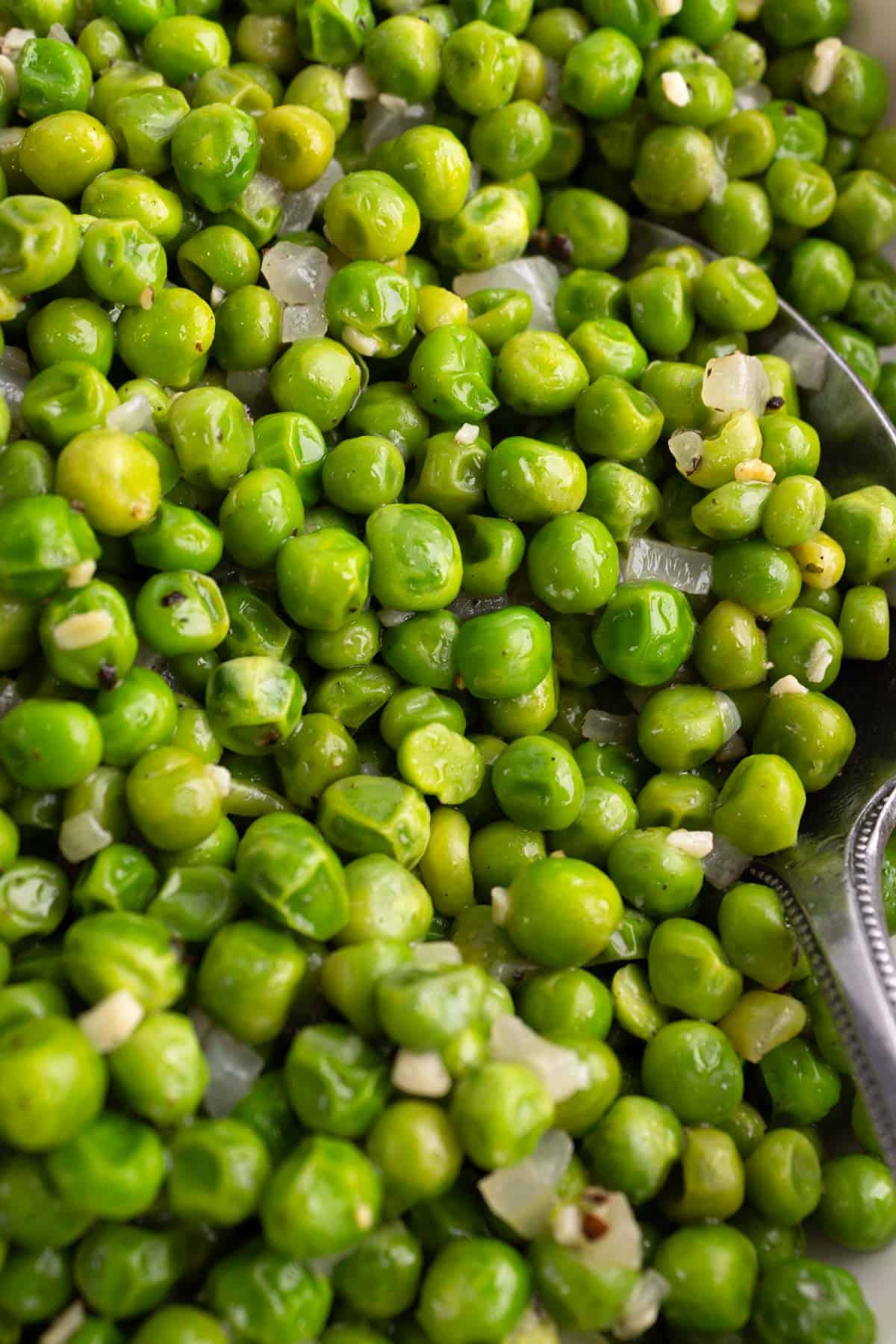 Closeup of a serving of skillet peas with a spoon.