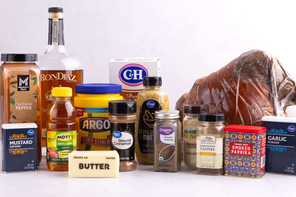 Seasonings, butter, corn starch, ham, spiced rum, and apple juice on a countertop.