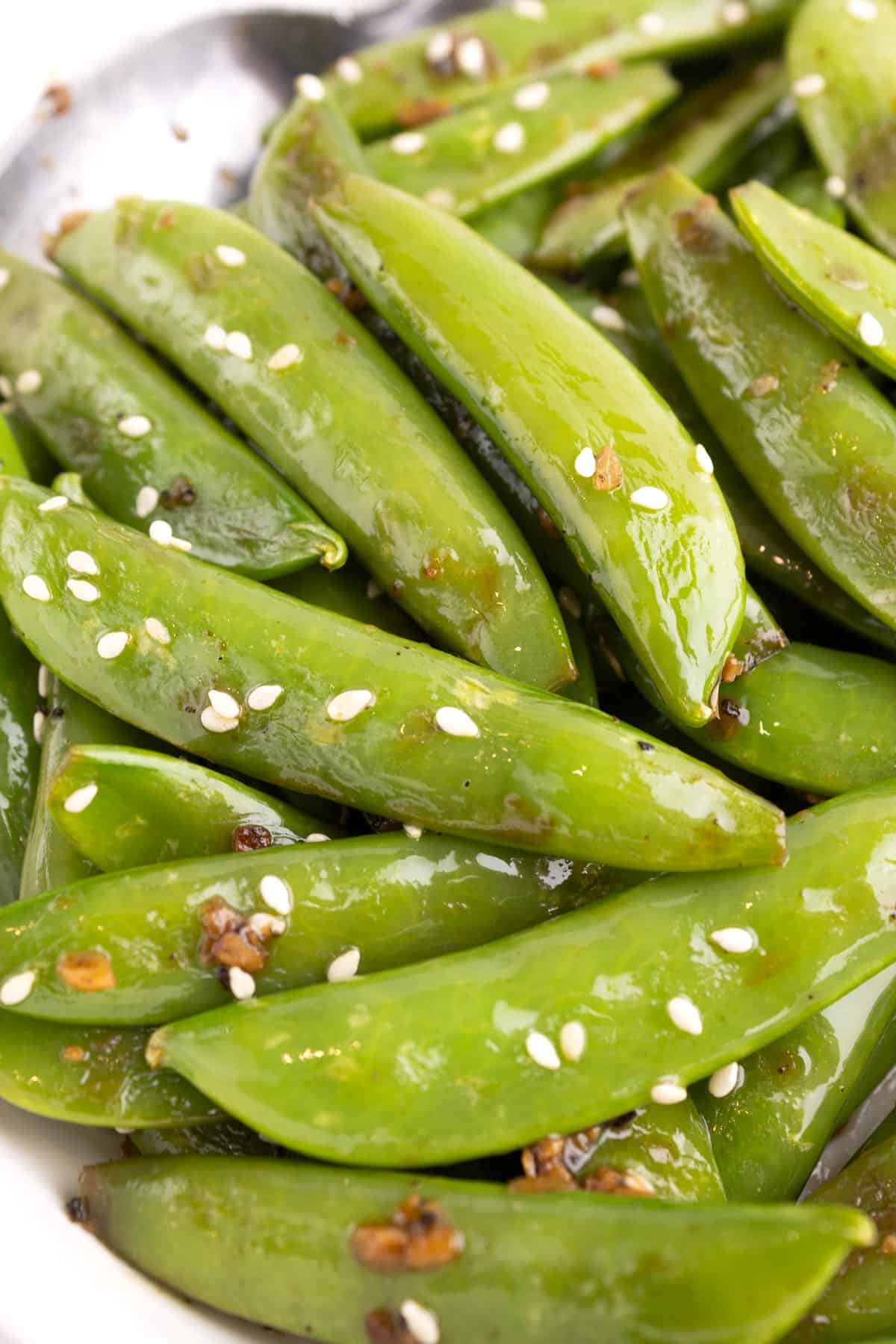 Closeup of cooked snap peas in a white bowl.