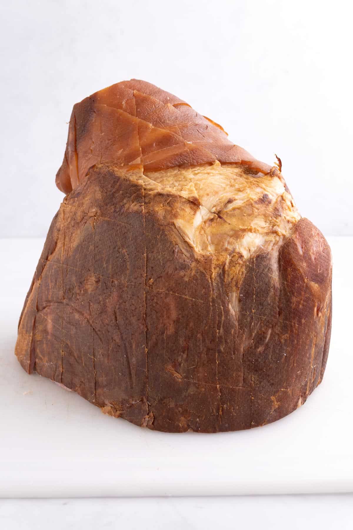 A large ham sitting on a white cutting board.