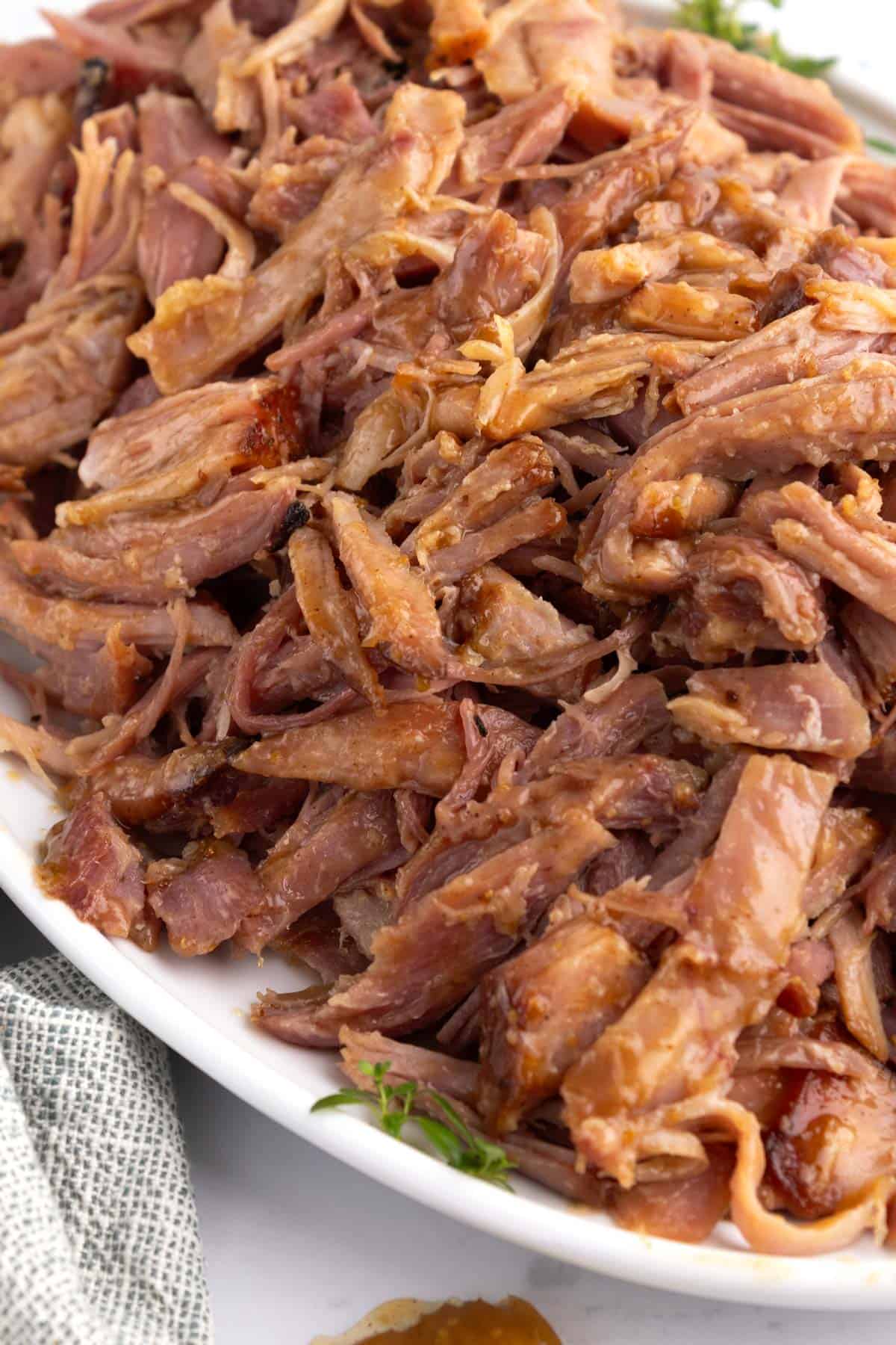 Smoked pulled ham on a glass serving platter.