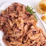 A tray of shredded ham and a glass container of glaze next to it.