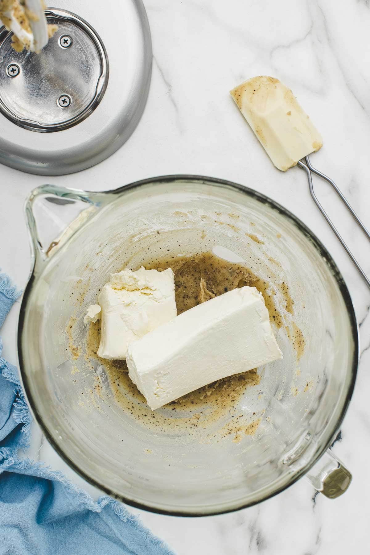 Cream cheese added to frosting mix with a spatula beside it.