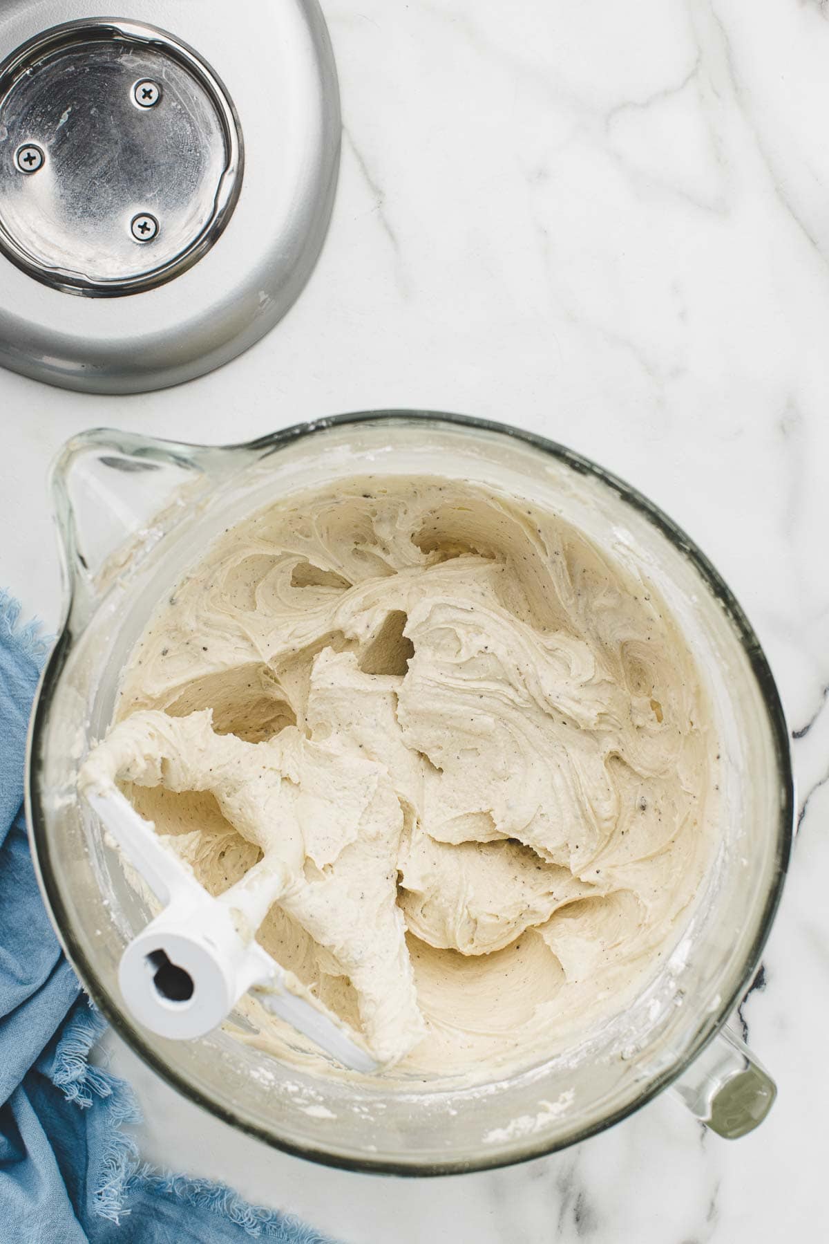 Blended cream cheese frosting with a mixing paddle in the bowl.