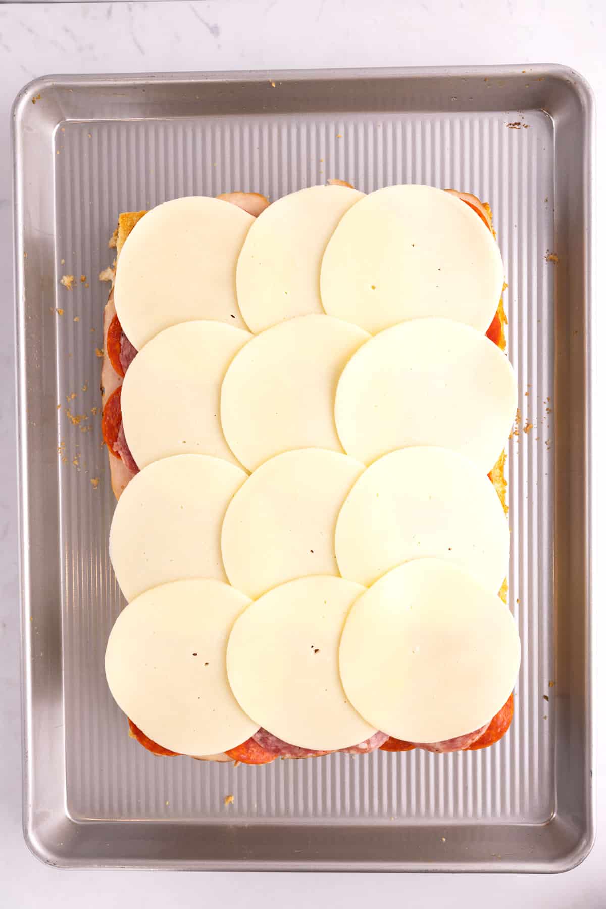 Cheese spread across several half-assembled sliders.