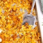 A pan of hash browns with a spatula.