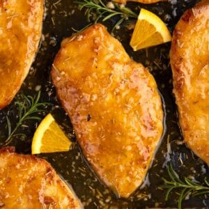 Orange rosemary chicken soaking in glaze in a skillet.