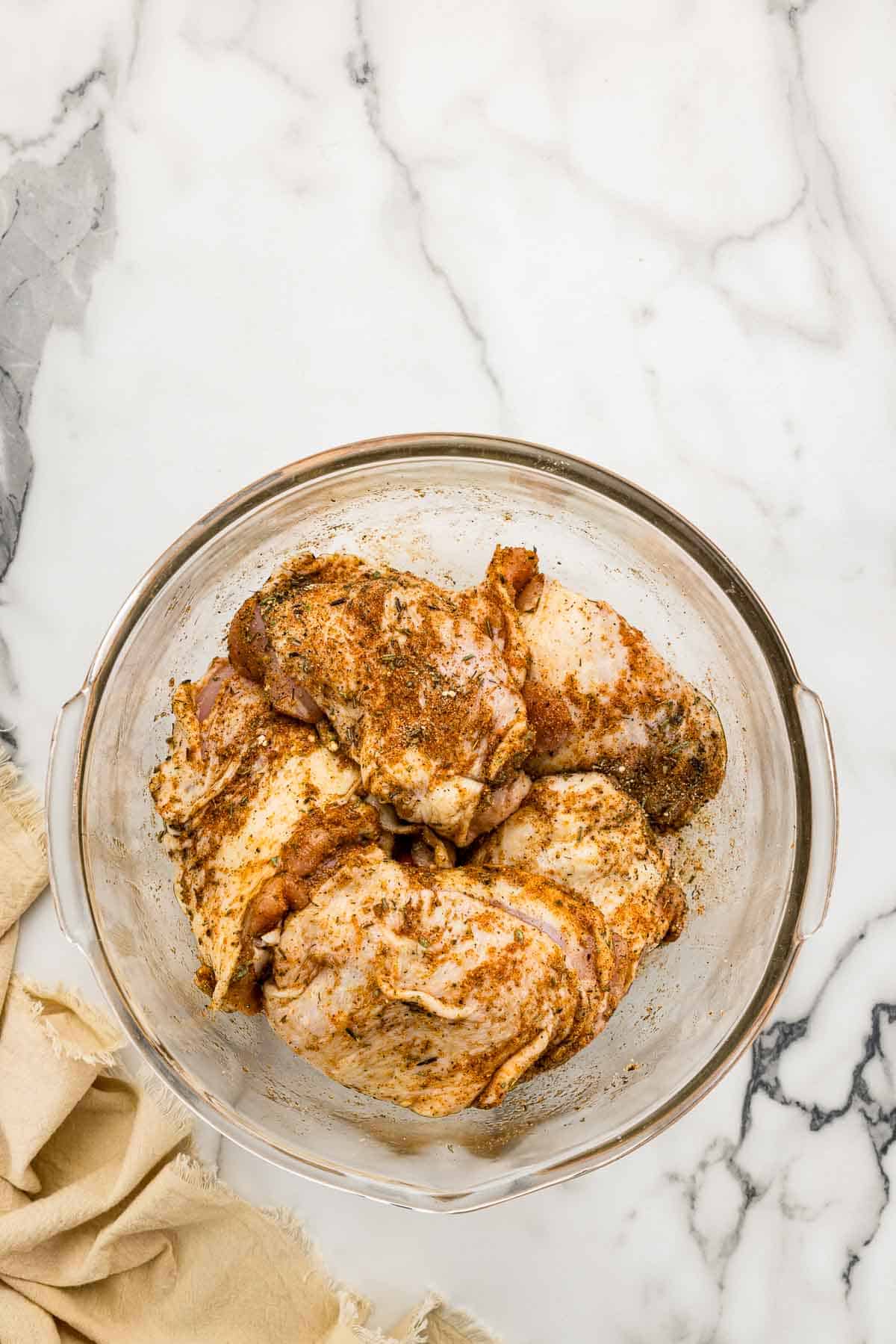 Seasoned chicken in a glass bowl.