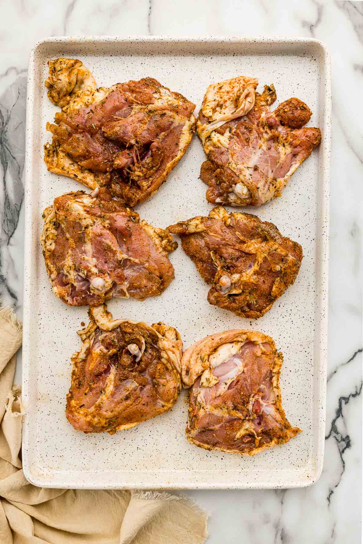 Raw chicken thighs on a sheet pan.