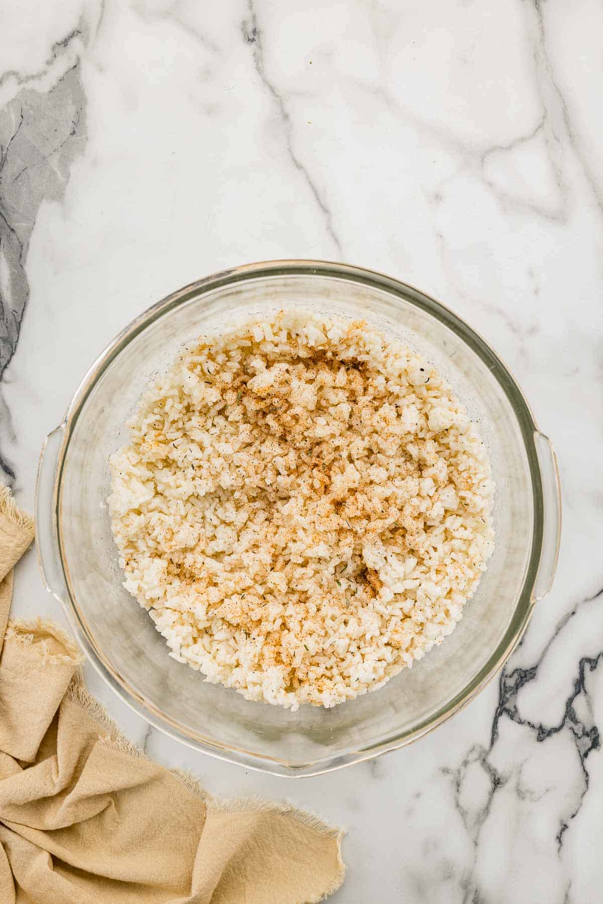 A glass bowl full of seasonings and rice.