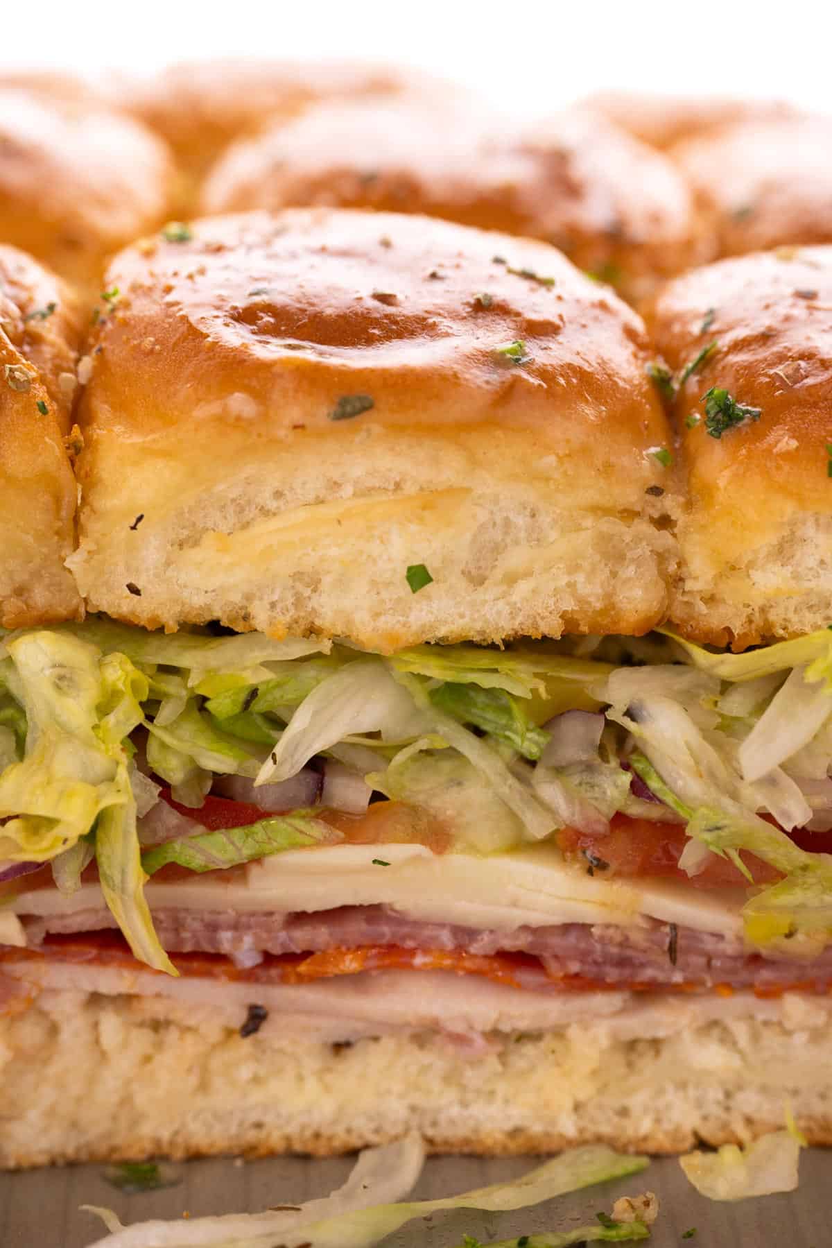Closeup of an italian slider full of meat, cheese, and lettuce.