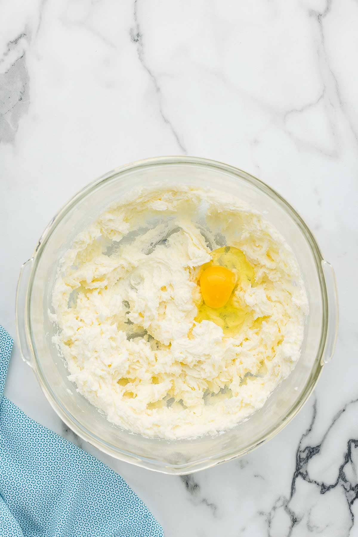 Eggs added to a glass bowl full of cookie dough.