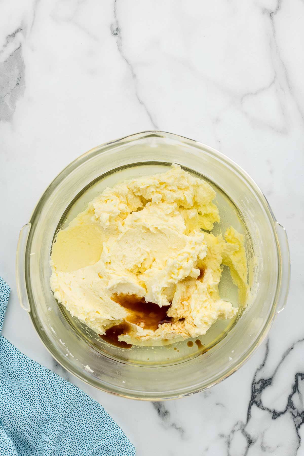 Vanilla and oil added to a glass dish full of cookie batter.