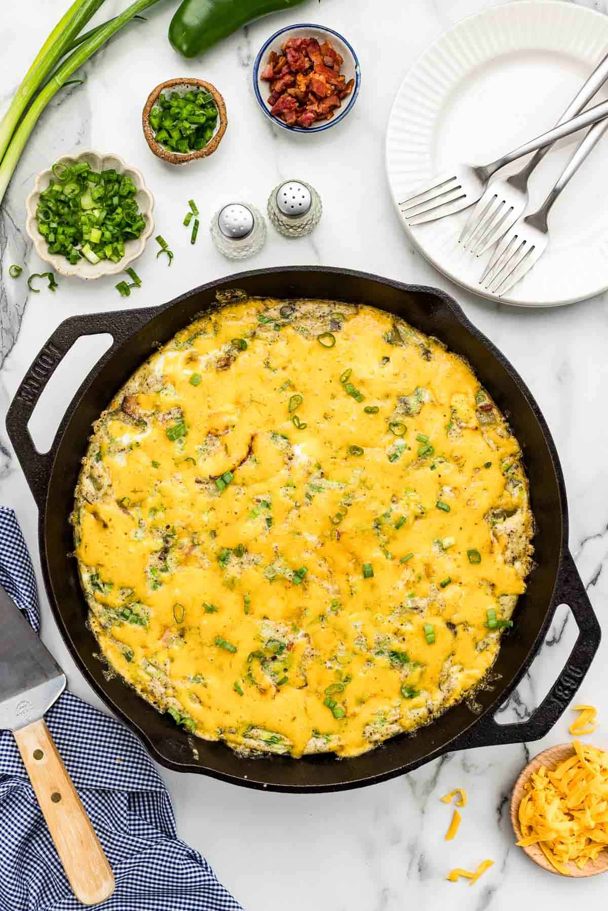 A breakfast skillet surrounded by an array of ingredients in small dishes.