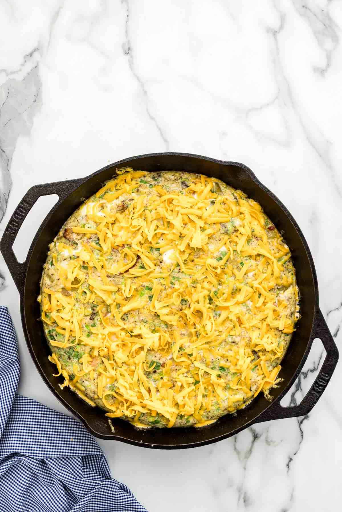 Cheese sprinkled over a breakfast bake in a skillet.