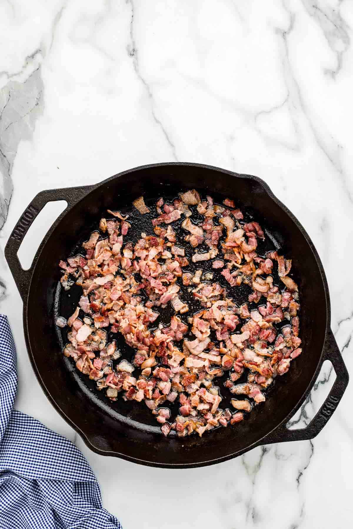 Bits of bacon cooking in a pan.