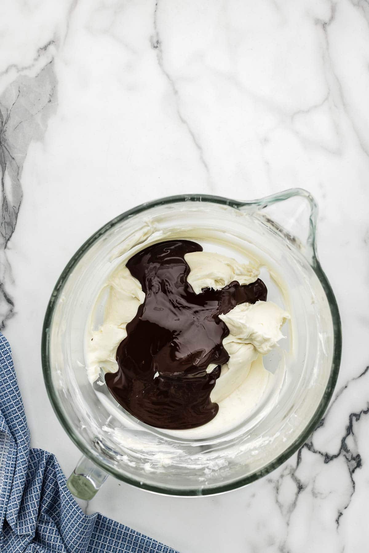 Cheesecake batter with chocolate added in a glass bowl.