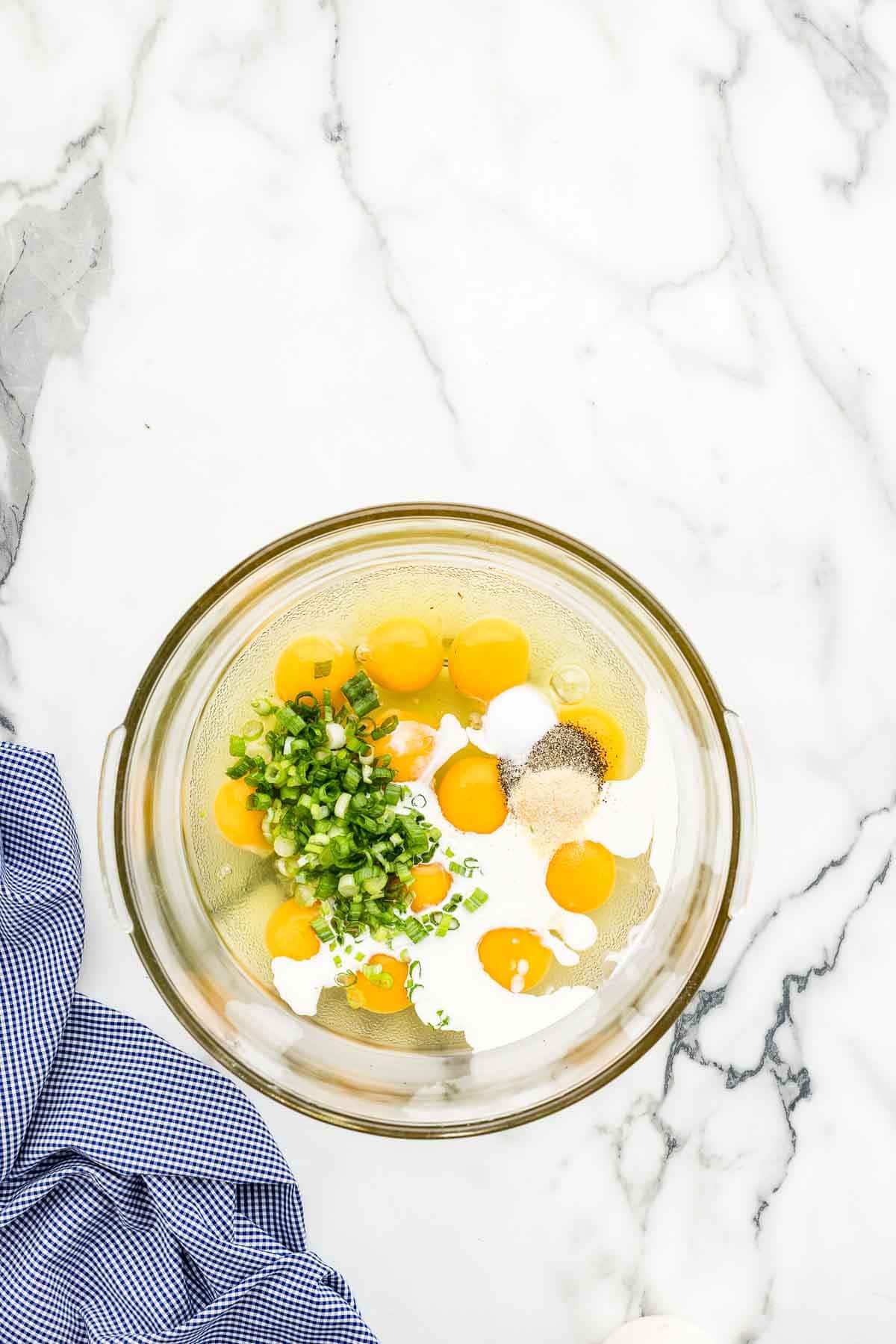 Breakfast bake ingredients in a glass mixing bowl.