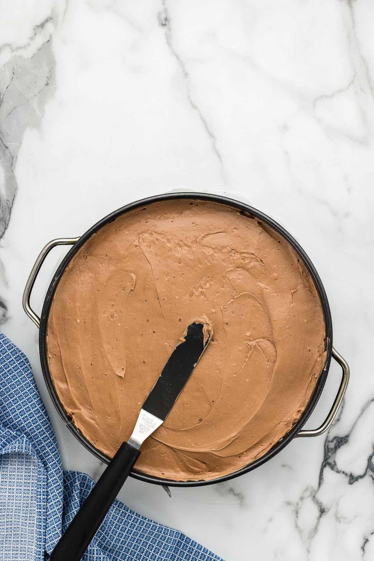 A spatula smoothing batter in a round pan.