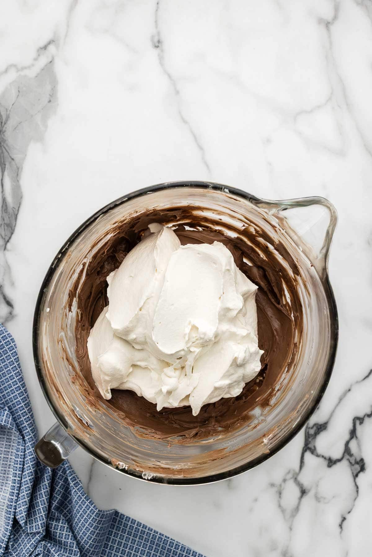 Whipped cream added to a mixing bowl of batter.
