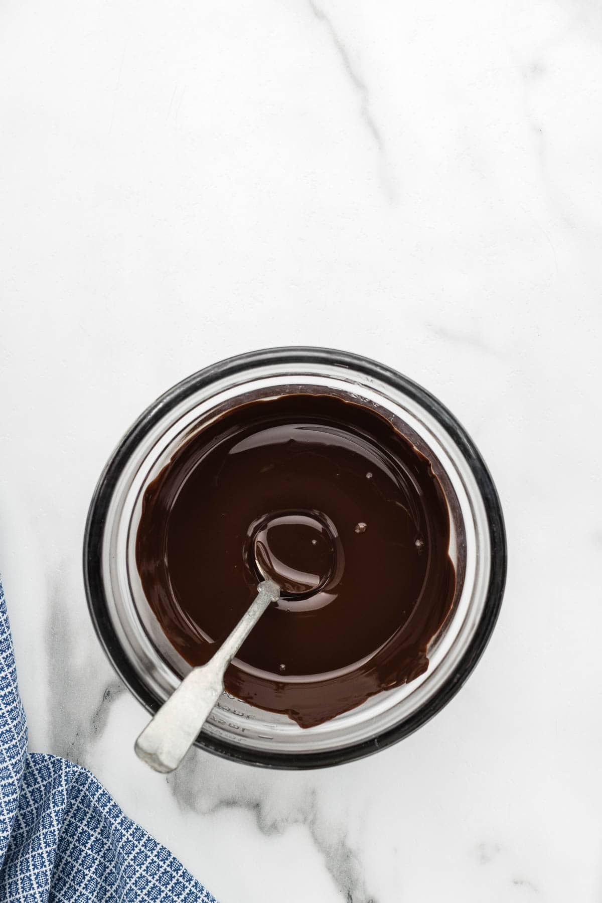 Melted chocolate in a measuring cup with a spoon.