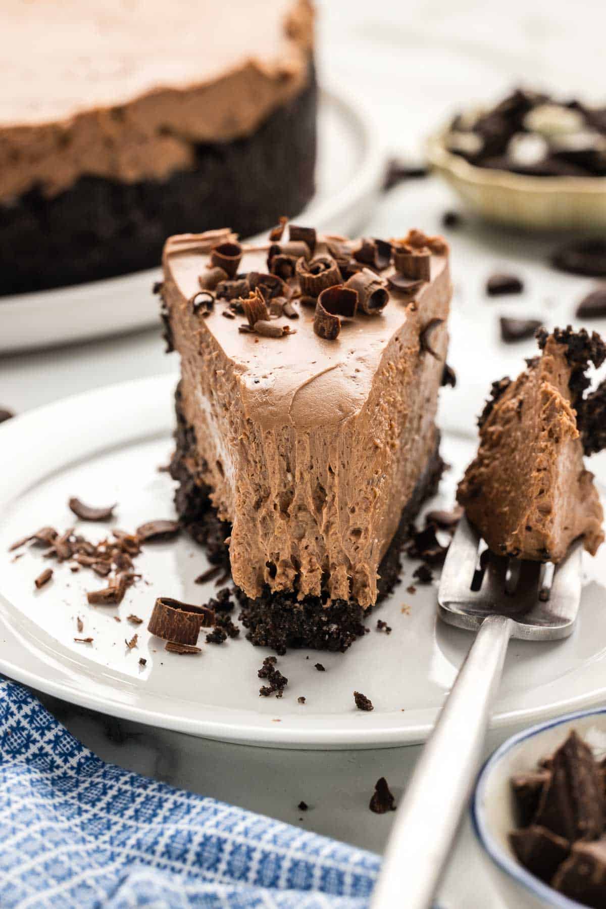 Closeup of a slice of cheesecake on a plate with a fork.